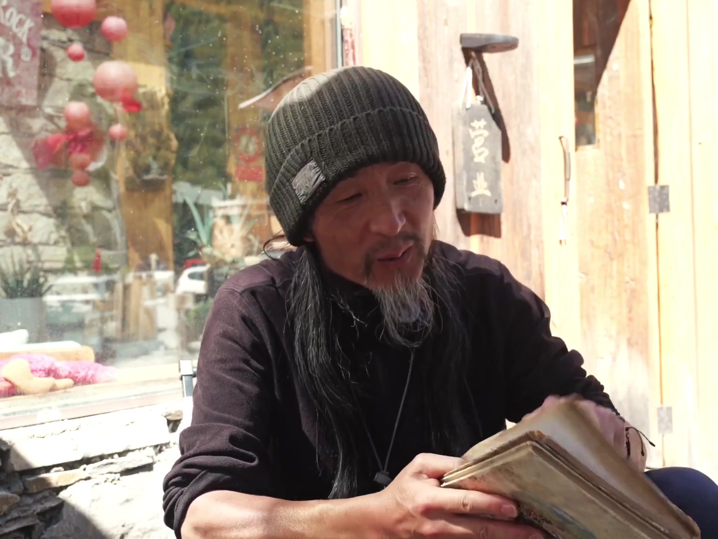 人物在镜头前讲述，手中拿着旧册子